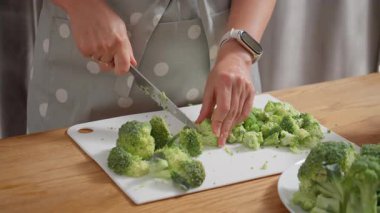 Sağlıklı bir diyet için yemek hazırlama süreci. Bir kadın taze yeşil brokoliyi çiçeklere ayırıp bu haftanın yemeklerini hazırlıyor. Beslenme, planlama ve ev yapımı gıdalara odaklanma.