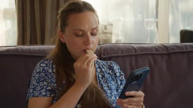 Bir kız şekerli gofret yer, işlenmiş yüksek kalorili abur cubur. Sağlıksız bir diyete, kötü beslenme alışkanlıklarına ve evde akıllı telefonuyla dikkatinin dağılmasına bir örnek..