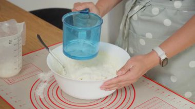 Ev yapımı ekmek için kalın bir hamur yoğuruyorum. Önlüklü bir kadın un ve suyu bir kasede kaşıkla karıştırır, geleneksel bir pizza ya da hasırın üzerinde turta hazırlar..