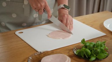 Kesme tahtasında jambon dilimleyen bir kadın. Lezzetli bir ev yemeği için salata, pizza, omlet ya da sandviç hazırlama süreci..