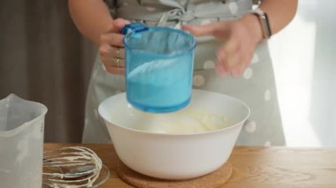 Mükemmel hamuru yapmak için aşçılık eğitimi. Bir ev hanımı ıslak malzemelere biraz un ekler ve geleneksel bir aile tarifi olan ev yapımı kek için hamur çırpar..