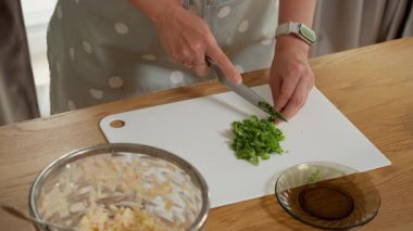 Kesme tahtasında fesleğen doğrayan bir şef. Aromatik yeşil bir garnitür hazırlama süreci ya da ev yapımı pesto sosu için sağlıklı, doğal içerikli bir temel hazırlama süreci..