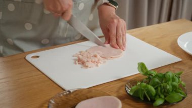 Lezzetli bir kahvaltı için meze etini küp küp doğramak. Bir kadın ev yapımı omlet, omlet ya da çırpılmış yumurta ve taze jambon hazırlar..