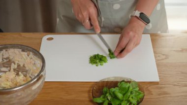 Yeşil otları doğrayarak ev yapımı yemeğe taze tat katmak. Bir kadın, turta, kiş ya da omlet için lezzetli bir dolgu yapmak adına taze fesleğeni ince ince keser..