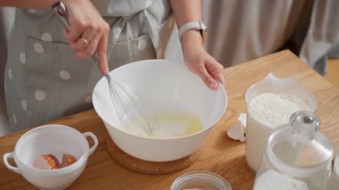 Kadınların elleri pürüzsüz bir hamuru yaratmak için kasede şekerli yumurta çırpıyor. Aile tarifine göre, ev yapımı tatlı, pasta ya da hamur işi için gereken malzemeleri hazırlama süreci.