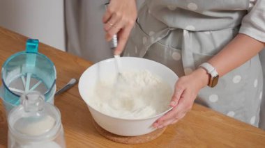 Bir kadın süt ve yumurta ile buğday unu çırparak pürüzsüz bir hamur hazırlar. Lezzetli ev yapımı krepler, turtalar ya da kekler için homojen hamur yapma süreci..