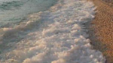 Crystal clear Adriatic sea waves gently wash over a beautiful pebble beach. An idyllic and popular seaside spot for a perfect summer family vacation. Clean water of a beautiful European resort.