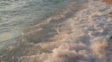 The calming and hypnotic motion of gentle sea waves on a pebble shore creates a tranquil background for meditation and relaxation. A peaceful, soothing nature scene for stress relief and mindfulness.