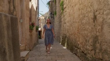 Confident solo traveler walking a narrow stone street on a summer holiday in Korcula. Concept of tourism, leisure and enjoying a trip to a beautiful and authentic European island destination.
