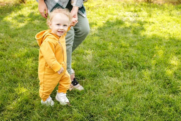 baby with mom takes the first steps in the park. child development