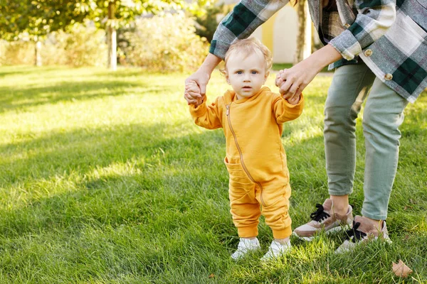 mom teaches baby to walk in the park for a walk