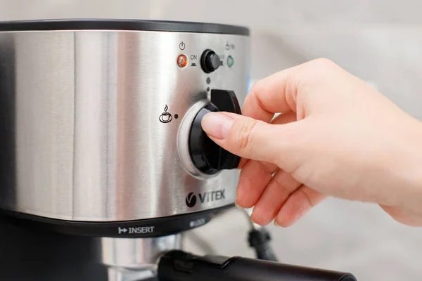 close-up woman turns on coffee machine at home