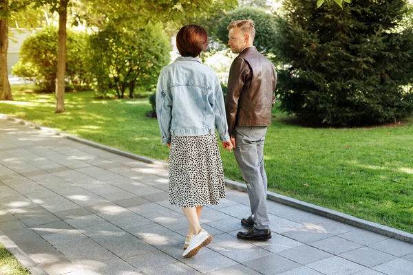 stock image happy couple walking in the park. back view