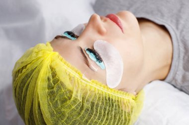 coloring and lamination of eyelashes to a woman close-up by a beautician