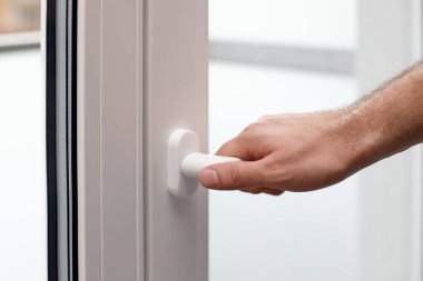 Close up a hand, holding handle of glass window to close or open. The concept of house maintenance, house equipment, building house, water leak prevention, window installation, get air ventilation.