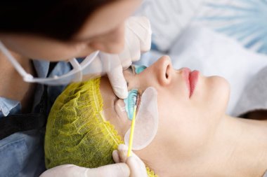 Usta kirpikleri yapıştırır. Kirpik kaldırma lamine botoks prosedürü sırasında güzellik modelinin yüzünün yakın çekimi. Kirpik Bakım Tedavisi: kaldırma ve kıvırma, kırbaçlama ve uzatma.