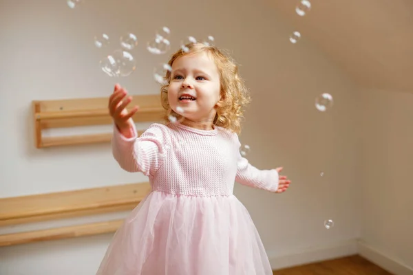 Портрет Маленькой Девочки Розовом Платье Играющей Мыльными Пузырями Дома — стоковое фото