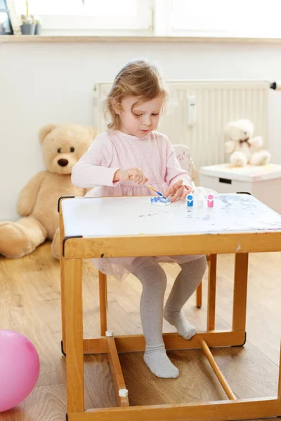 女の子は子供のテーブルで家で絵を描く 就学前教育 — ストック写真