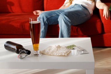 Evdeki kötü alışkanlıklarda masada alkol ilaçları var. Arkadaki kadın.