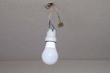 Tavandaki bir kabloda ampul. Evde elektrik var. Tehlike.