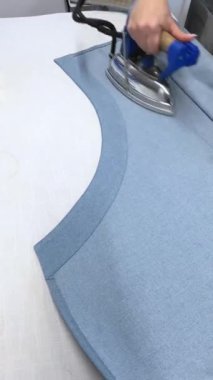Dişi bir terzi kadın ütü diker kot elbise diker. Moda uzmanı, moda fabrikası veya stüdyo, atölye, bir tasarım girişimi vizyonu.