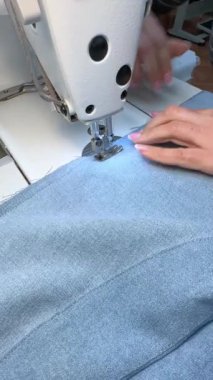 Dişi bir terzi kot bir etek dikiyor. Bir moda uzmanı, bir moda fabrikası veya stüdyo, bir atölye, bir tasarım girişimi vizyonu.