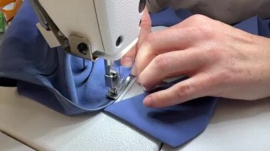 Bir kadın terzi dikiş makinesine elbise dikiyor. Bir moda uzmanı, bir moda fabrikası veya stüdyo, bir atölye, bir tasarım girişimi vizyonu.