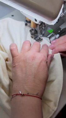 Dikiş işlemi. Bir terzi örgü kumaş diker, ürünün işleme bölümünü profesyonelce kapatır. Atölyedeki elbise dikişlerini dikmek, kıvırmak ya da katlamak için bir dikiş makinesi.