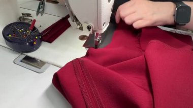 Pantolon dikme süreci. Yetenekli bir zanaatkar kumaşı ustalıkla iğneleyip canlı kırmızı bir renk yaratmak için özel teknikler sergiliyor..