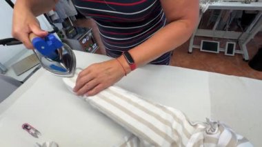 Etkili teknikler ve beceriler sergileyen çizgili bir gömleğin nasıl ütüleneceğini gösteren bir kişi. Bireyler kumaşı dikkatlice ütü masasına yerleştirir, buhar ütüsüyle kırışıklıkları temizler..