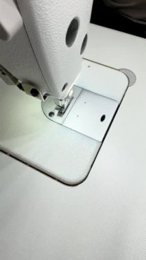 Bir kadın terzi etek diker, beyaz kadife pantolon, kadife pantolon, moda uzmanı, moda fabrikası ya da stüdyo, atölye, yeni bir tasarım vizyonu. Dikey video.