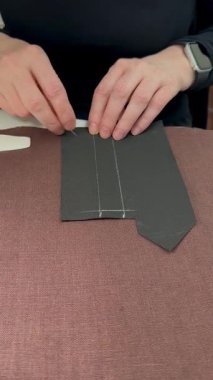 İşaretlemeden Makine Dikişine Terzilik İşlemi. Terzilerin ellerini kapat, beyaz tebeşirle siyah kumaşa dikiş rehberi çiz. Moda stüdyosundaki giysi hazırlıklarının detaylı görüntüsü.