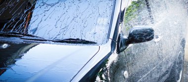 Araba yıkama çubuğuyla siyah araba yıkamak.