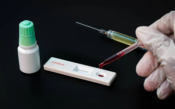 Doctor drops blood on test kit for COVID-19 viral disease, test card set for novel virus, rapid test set for coronavirus covid-19.