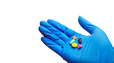 Tabletler, farklı renkler, doktor eli, beyaz üzerine mavi tıbbi eldiven giyerek kesme yolu..