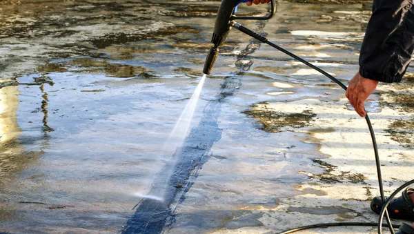 İşçiler çatı temizlemek için su püskürtücü kullanırlar 