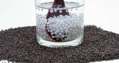 Tahta kaşıkta fesleğen tohumu. Beyaz arka planda bir bardakta fesleğen tohumu. Sağlıklı yiyecek..