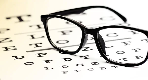 Black eyeglasses in eye test chart on a white background.