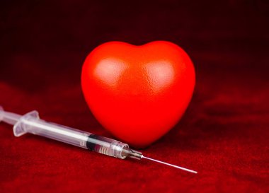 Koyu arkaplanda kırmızı kalp ve şırınga