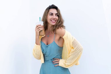 Portrait of beautiful woman in green summer dress on white background natural daylight, holding iced coffee cappuccino happy smiling excited