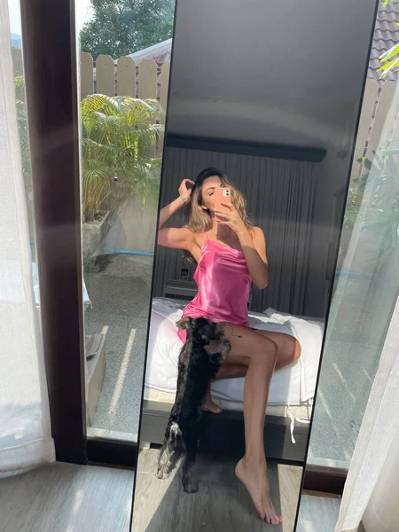 フィット日焼けした女性でピンクシルクショートスリープドレスで自宅取る写真自撮りで電話でミラーのためのソーシャルメディア — ストック写真