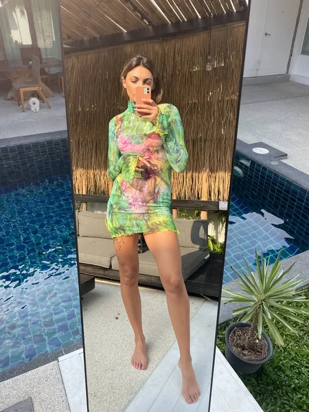フィットスポーティーな日焼けした女性で緑の短い透明ドレス屋外で自宅で写真を撮る上の電話でミラー用ソーシャルメディア 垂直プールによって — ストック写真