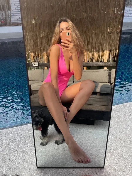 フィットスポーティな日焼けした女性で明るいピンクの水着屋外で自宅で写真を撮る上の電話で鏡の中にソーシャルメディア 垂直プールによって — ストック写真