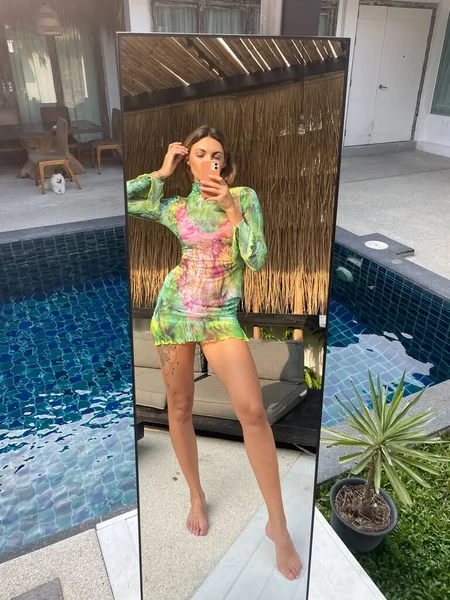 フィットスポーティーな日焼けした女性で緑の短い透明ドレス屋外で自宅で写真を撮る上の電話でミラー用ソーシャルメディア 垂直プールによって — ストック写真