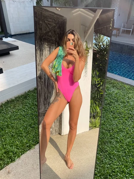 在户外 穿着亮晶晶粉色泳衣的体态丰满的晒得发亮的女人在手机上拍照 在社交媒体 垂直的镜子中拍照 — 图库照片
