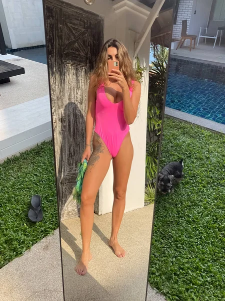 フィットスポーティな日焼けした女性で明るいピンクの水着屋外で自宅で写真を撮るの携帯電話でミラー用ソーシャルメディア — ストック写真