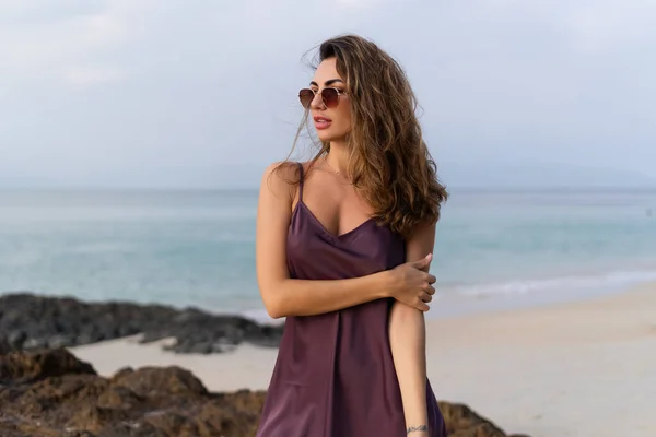 日落时分 沙滩上穿着丝绸衣服和太阳镜的时尚浪漫而柔嫩的性感女人 — 图库照片