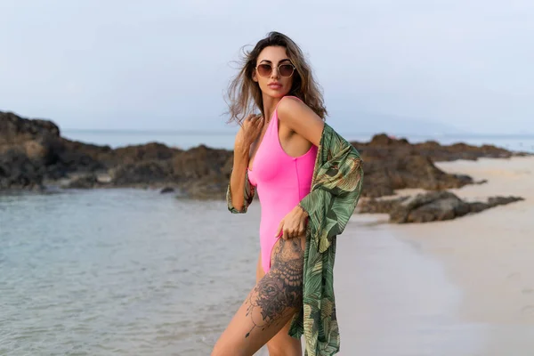 日落时分 海滩上穿着粉色泳衣 热带和服和太阳镜的时尚浪漫而纤细的性感女子 — 图库照片