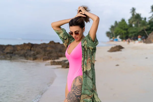 日落时分 海滩上穿着粉色泳衣 热带和服和太阳镜的时尚浪漫而纤细的性感女子 — 图库照片
