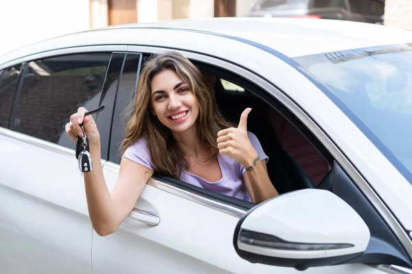 stock image Beautiful young happy smiling woman driving her car, showing the keys to a new car